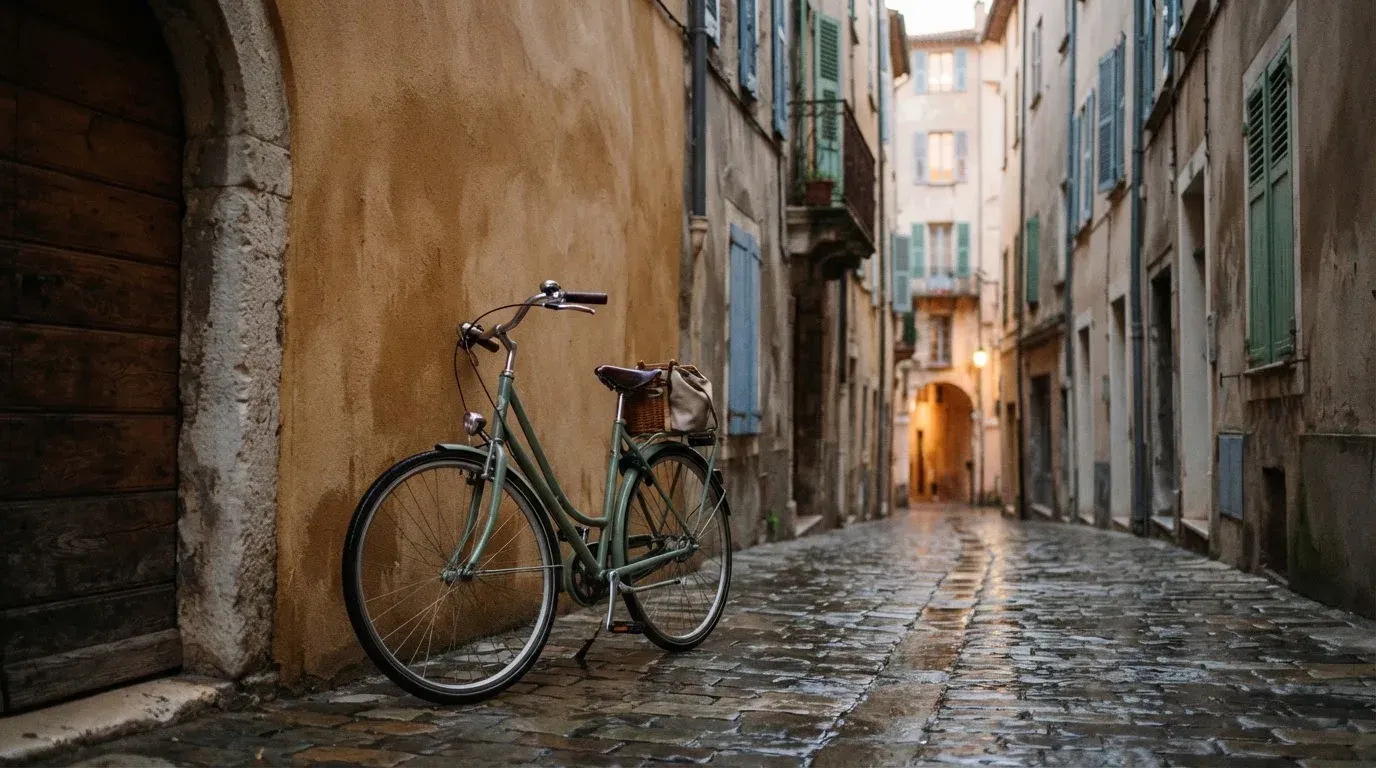 Ein Fahrrad lehnt an einer Mauer in einer Altstadtgasse, das Kopfsteinpflaster glänzt nass nach dem Regen.