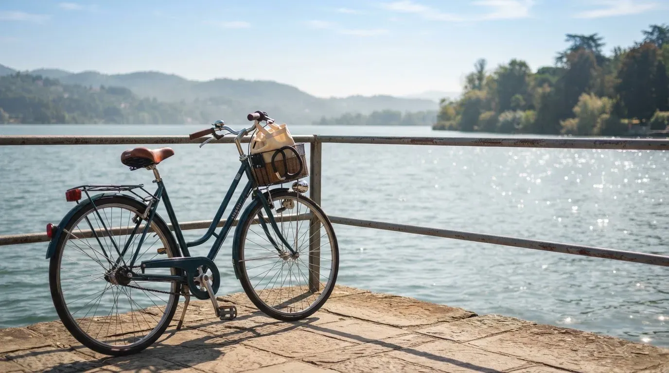 Ein Fahrrad lehnt an einem Geländer einer Uferpromenade an einem See im Sonnenlicht.