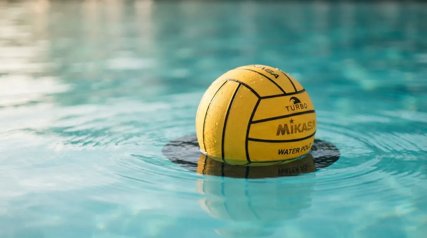 Ein gelber Ball treibt auf ruhigem türkisfarbenem Beckenwasser, feine Wellen im weichen Licht.