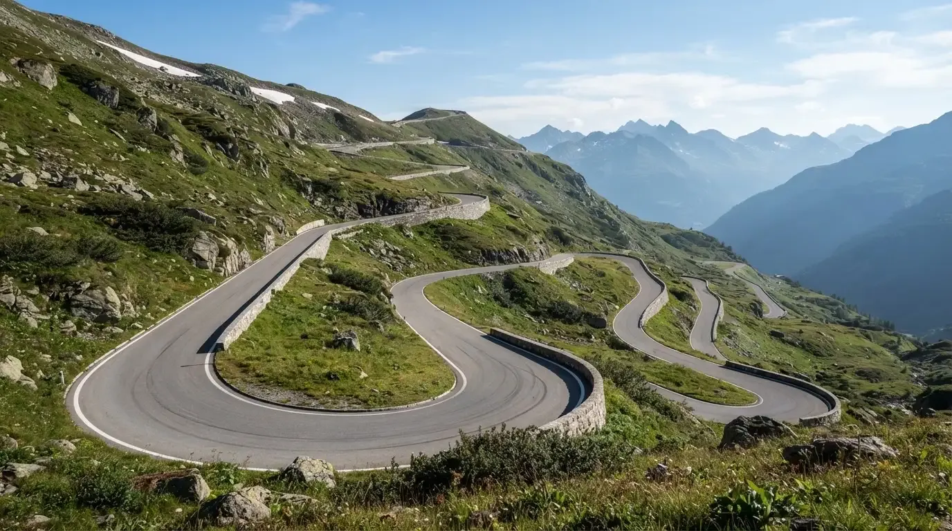Eine Passstrasse zieht sich in Kehren einen Alpenhang hinauf, kein Fahrzeug ist zu sehen.