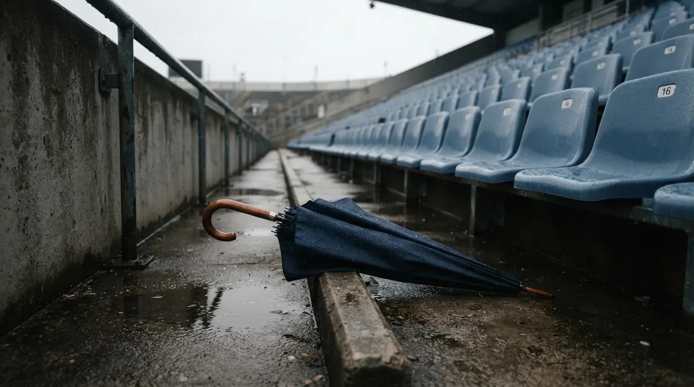 Ein Regenschirm liegt auf einer nassen Treppe zwischen leeren Zuschauerrängen.